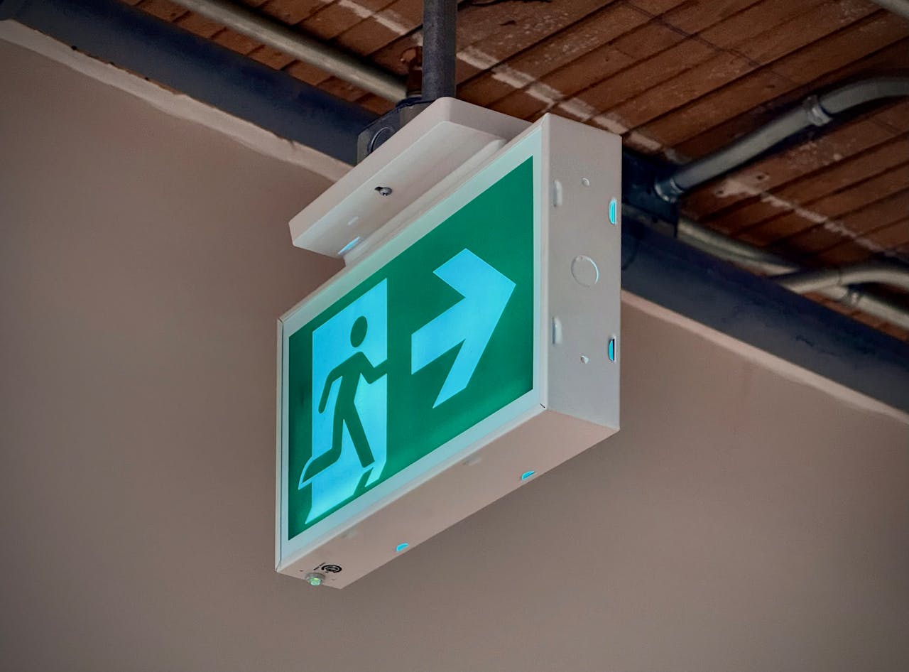 Home Green emergency exit sign with an arrow indicating direction inside a building.