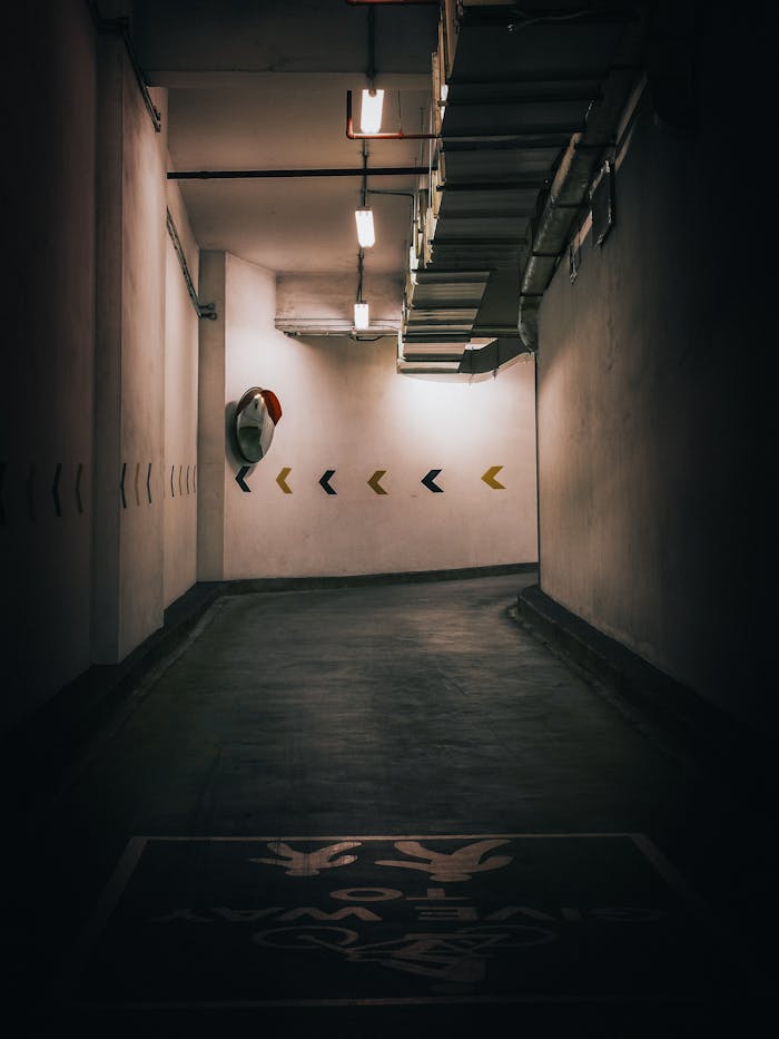 Home Dimly lit underground parking garage with directional signs and a moody atmosphere.